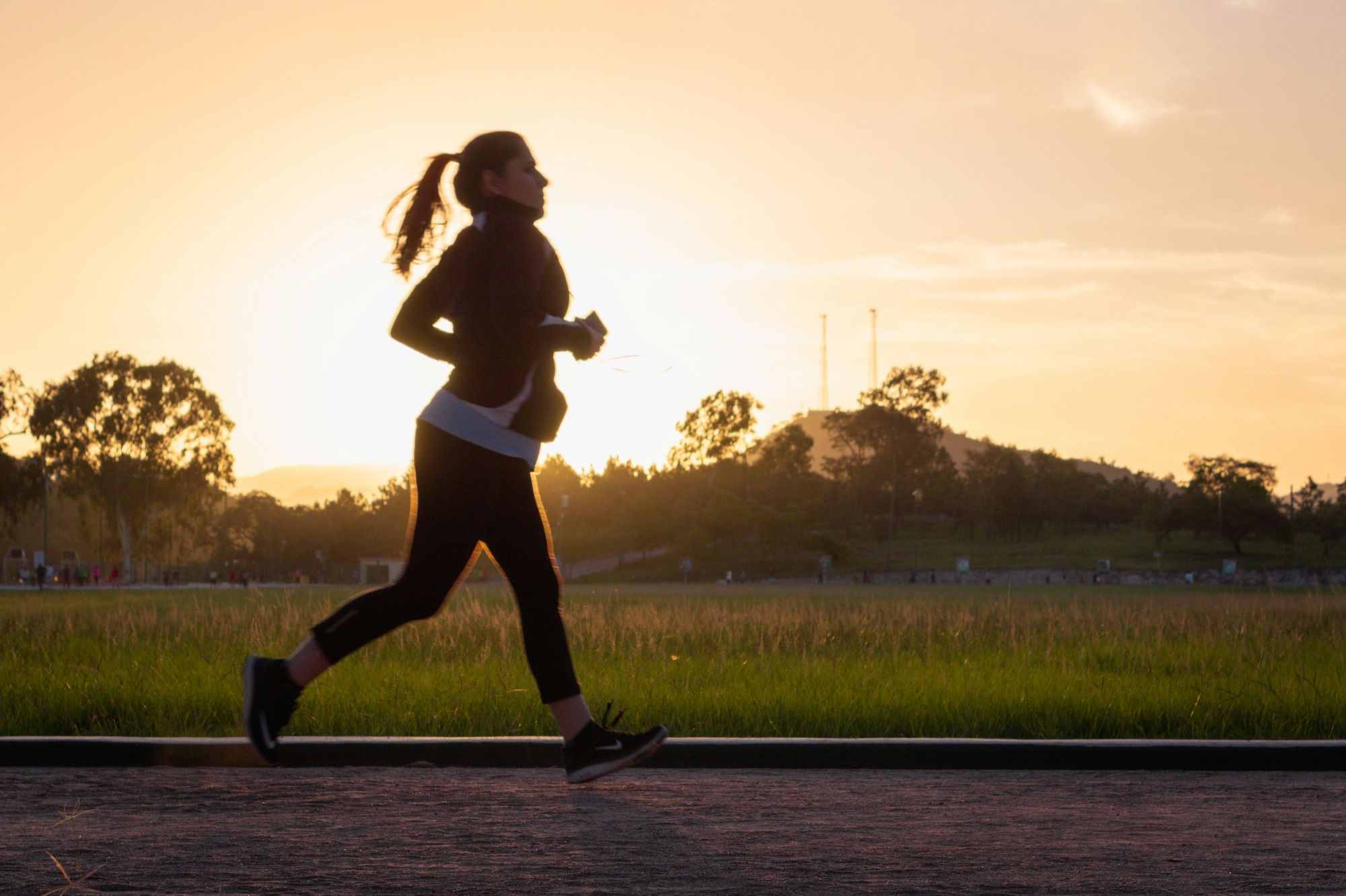 A runner mid-stride against a golden-hour sky, silhouetted in profile